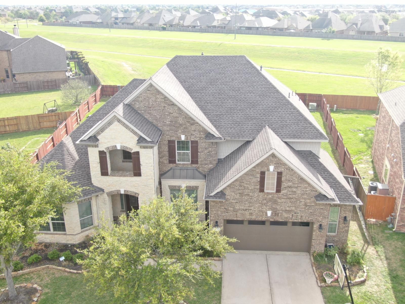 Completed shingle roofing on a brick and stone home