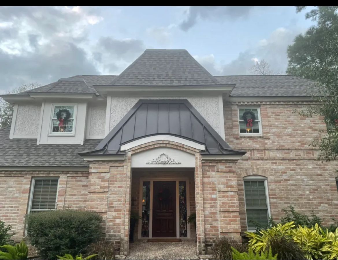 Front view of a brick home with shingle roofing and a metal entryway roof