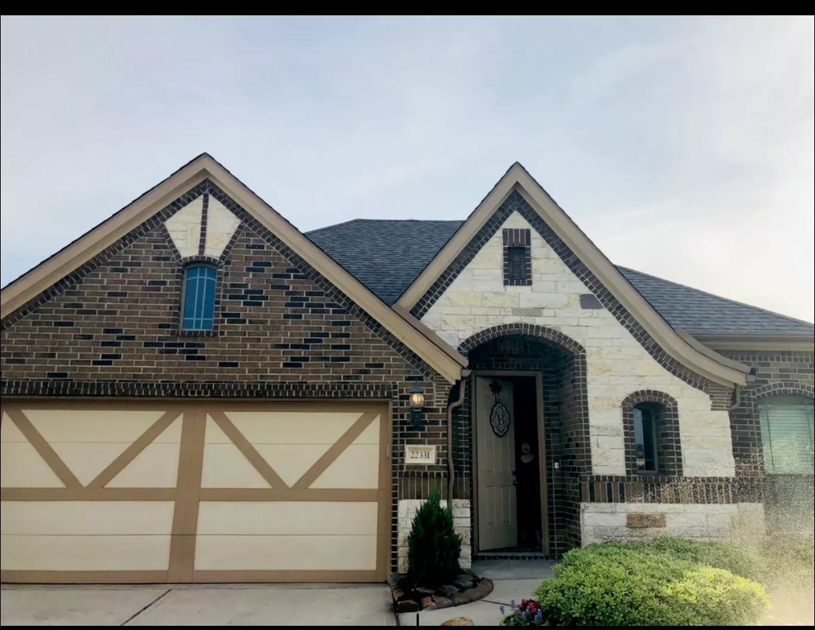 Front elevation of a brick and stone home with shingle roofing